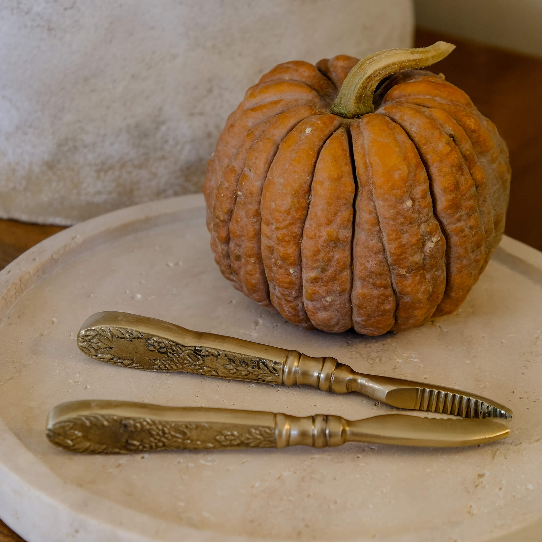 Set aus Messern aus Messing mit verzierten Griffen auf beigem Tablett neben orangefarbener Kürbisdekoration