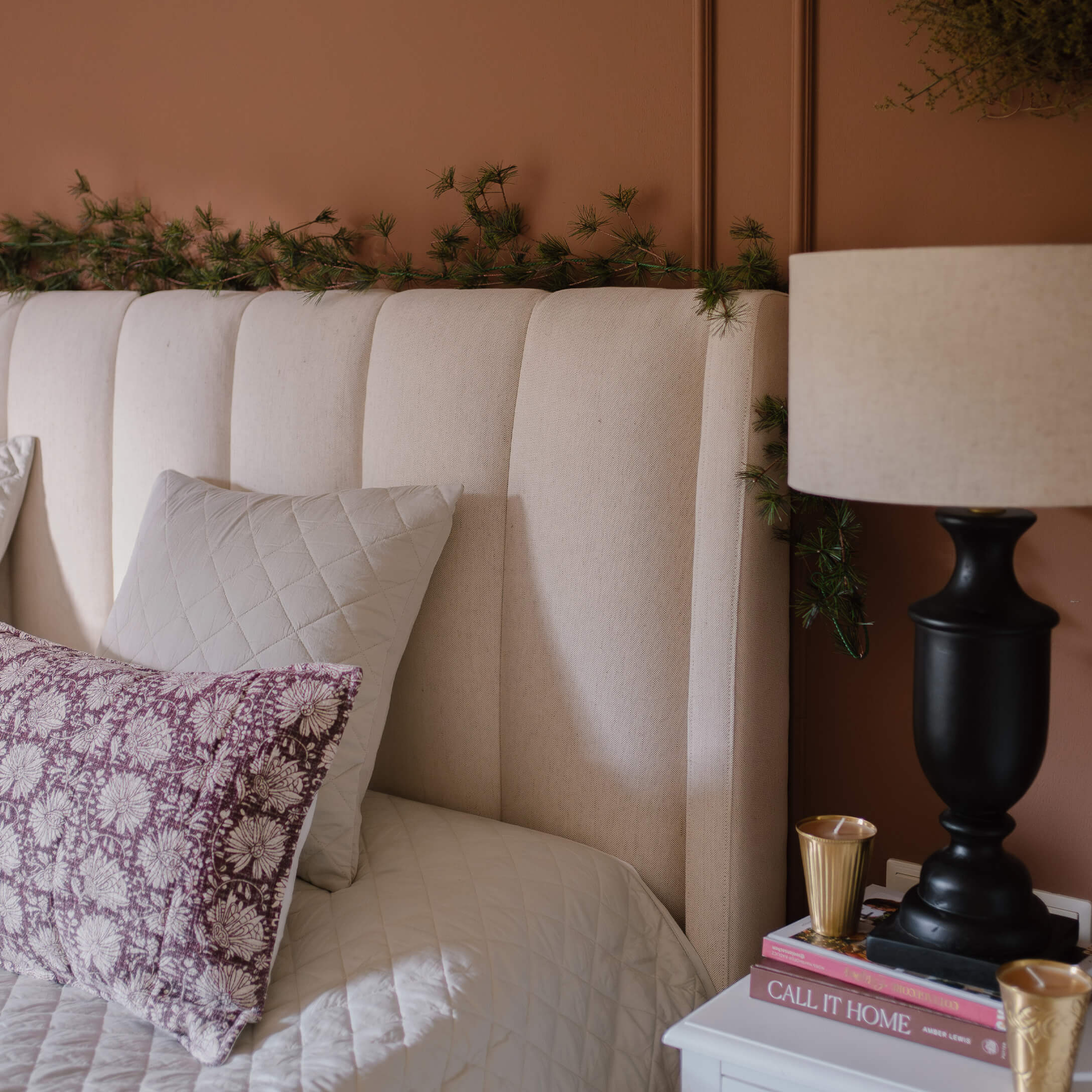 Beiges gepolstertes Kopfteil mit Kissen und Lampe auf Nachttisch in gemütlichem Schlafzimmer