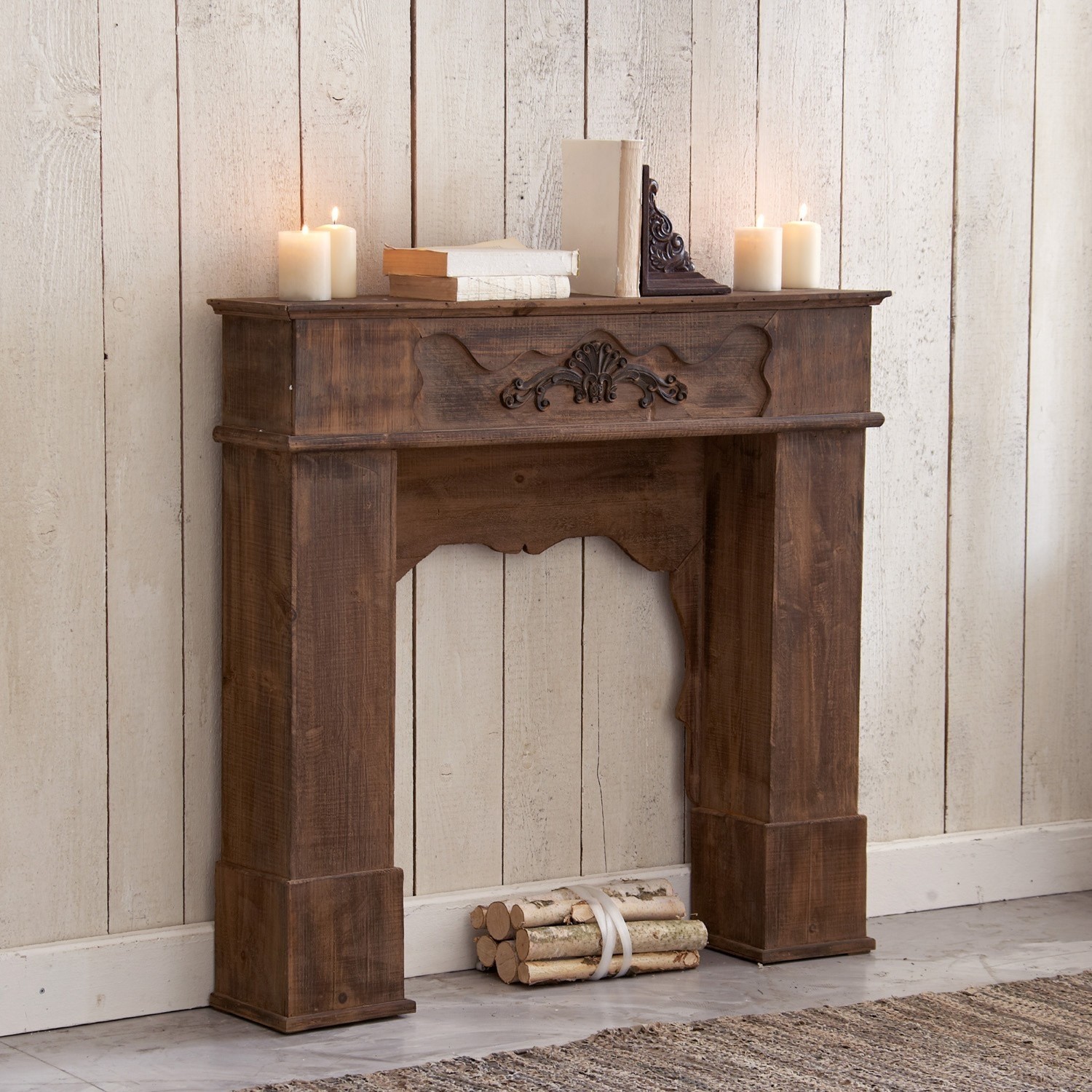 Kaminkonsole Margaux Dekorativer Kamin aus dunklem Holz mit geschnitztem Muster, dekoriert mit Kerzen und Büchern