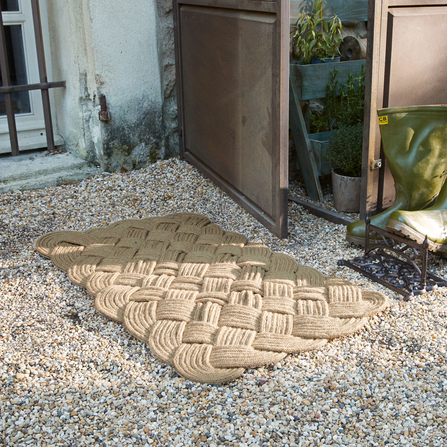 Fußmatte Harman Beige Fußmatte aus geflochtenem Seil auf Kiesboden vor offener Tür neben grünen Gummistiefeln