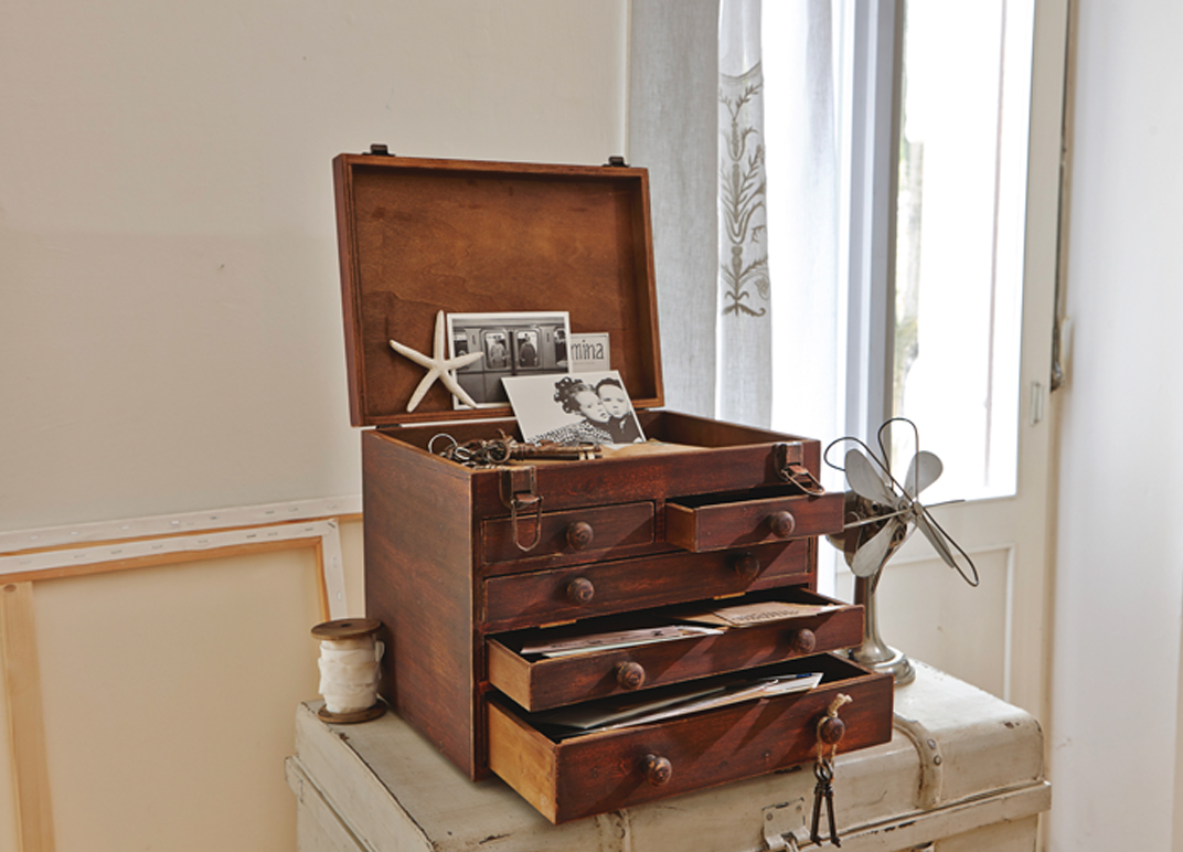 Vintage Holzbox mit Schubladen und offenem Deckel, gefüllt mit Fotos und Dokumenten in hellem Raum