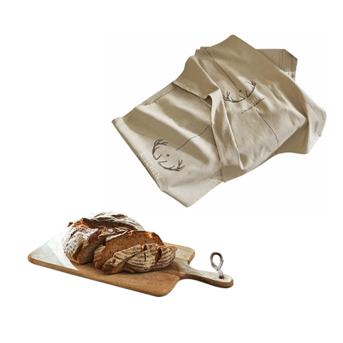 Beige Leinentischdecke mit Hirschgeweih-Motiv neben Holzschneidebrett mit Brot