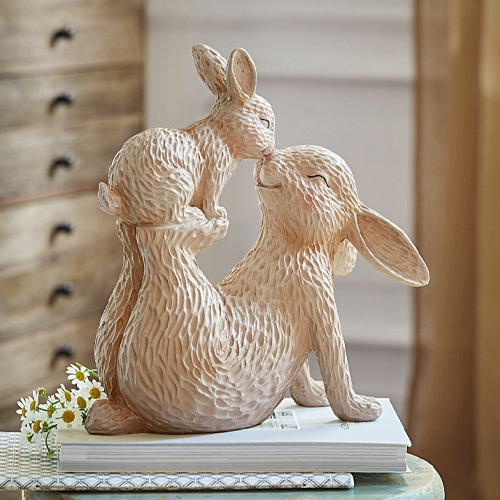 Beige Keramikfigur zweier kuschelnder Hasen auf Büchern, zarte Frühlingsdekoration für Zuhause