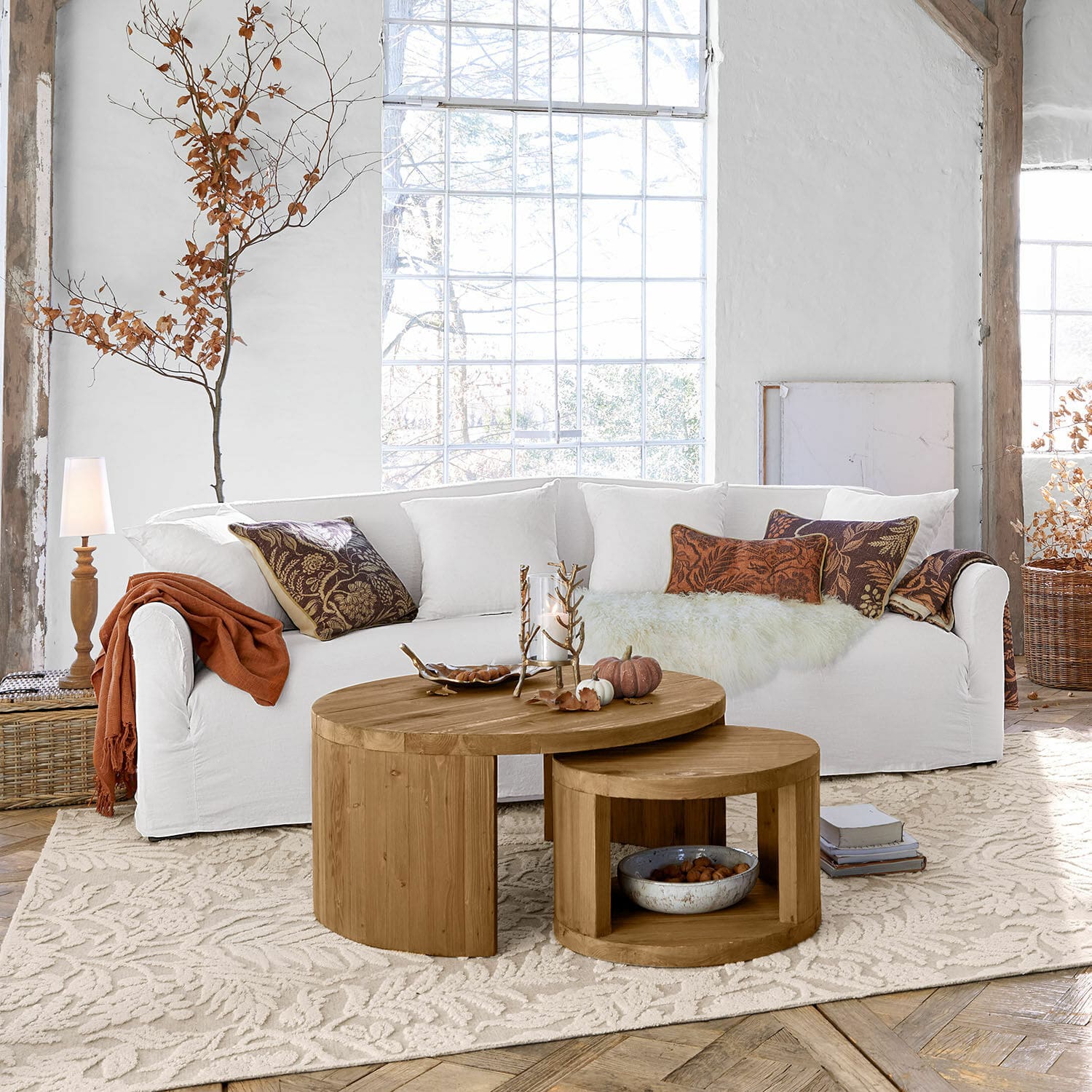 Sofa Riveneuve Zwei runde Couchtische aus naturfarbenem Eichenholz auf hellem Teppich im Wohnzimmer