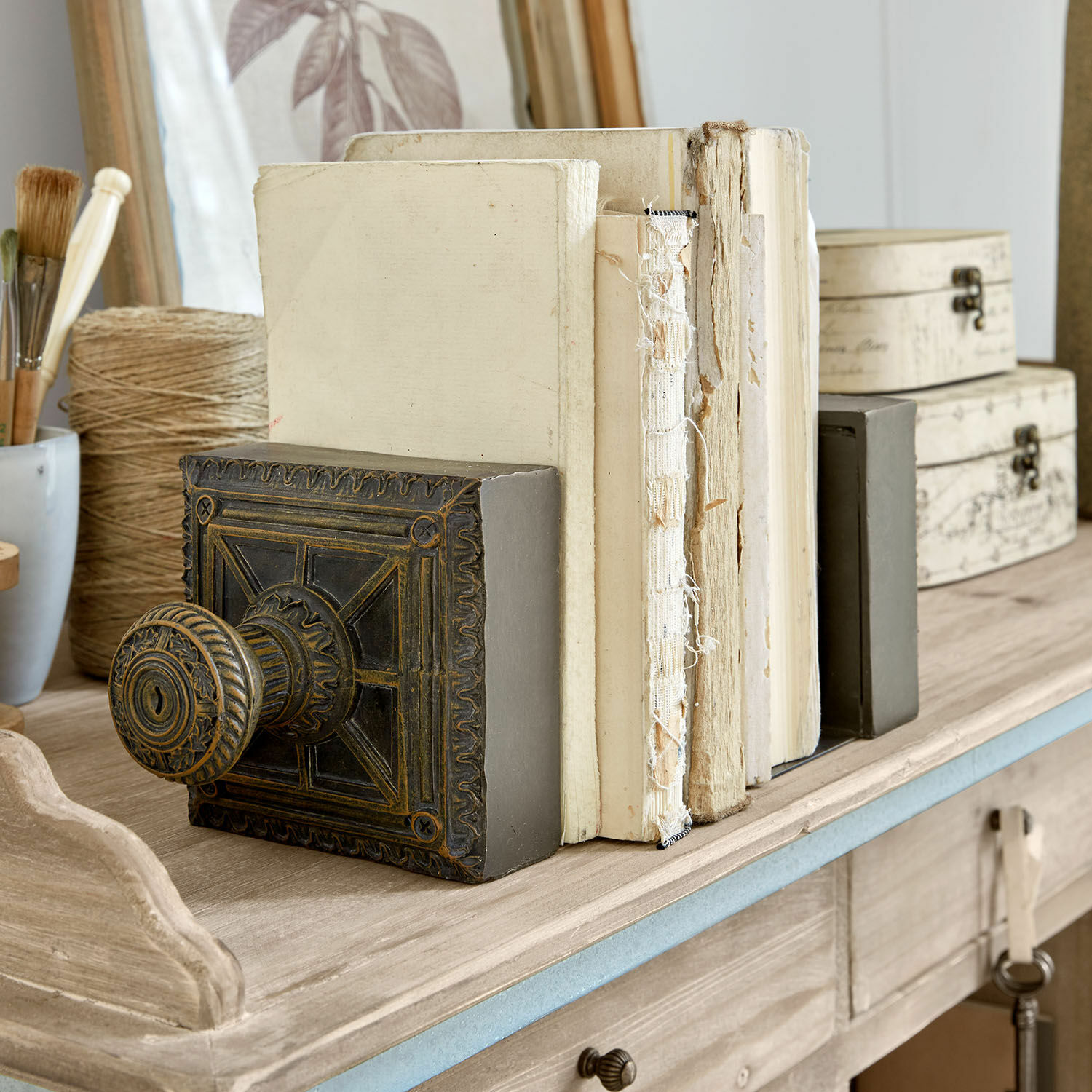 Verzierter schwerer Buchstütze aus dunklem Metall auf Holztisch mit alten Büchern