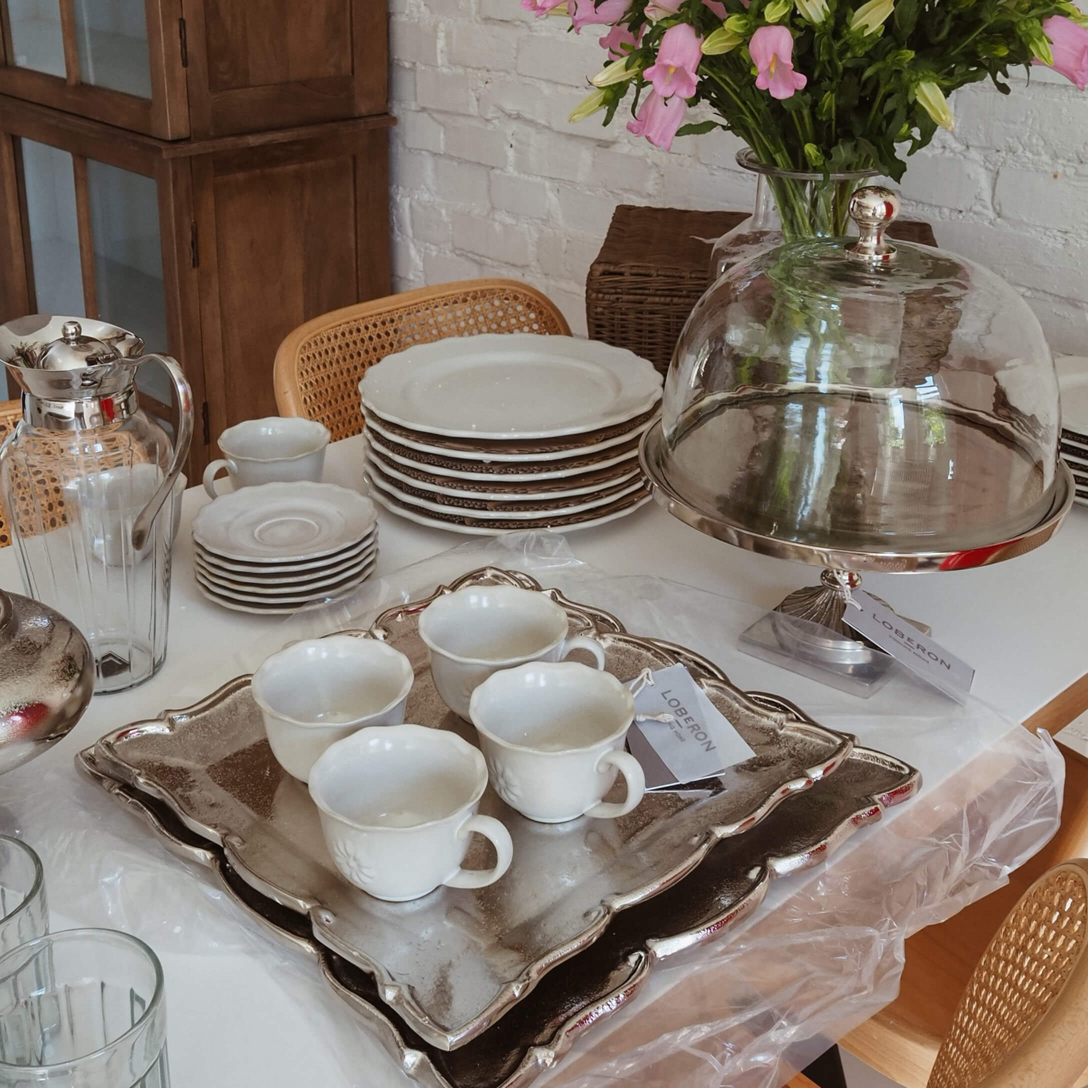 Weißes Porzellan mit Tassen und Tellern auf silbernem Tablett, Slow-Living-Tischdekoration