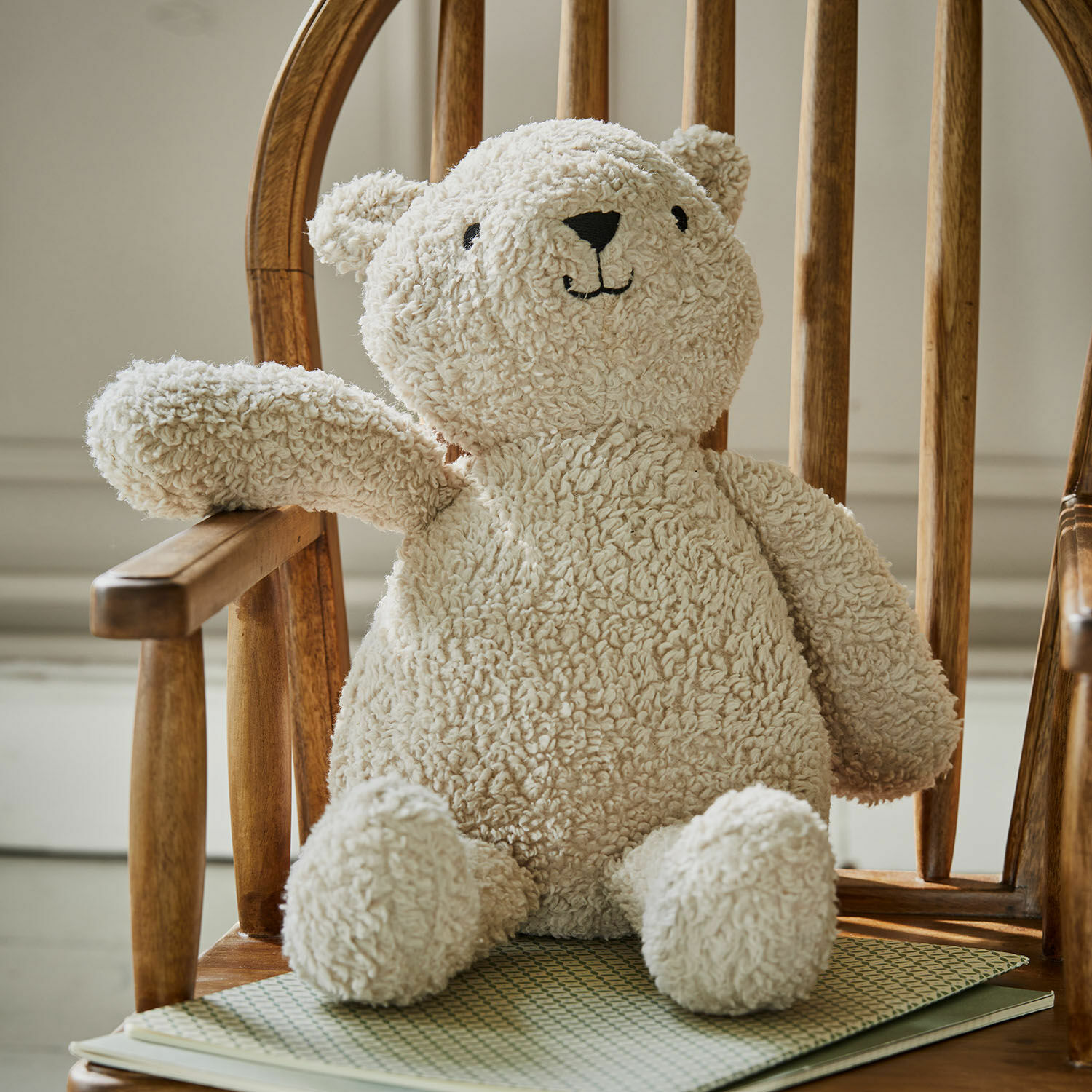 Stofftier Fuffino Kuscheliger Teddybär aus cremefarbenem Plüsch auf Holzstuhl, Kinderzimmerdeko