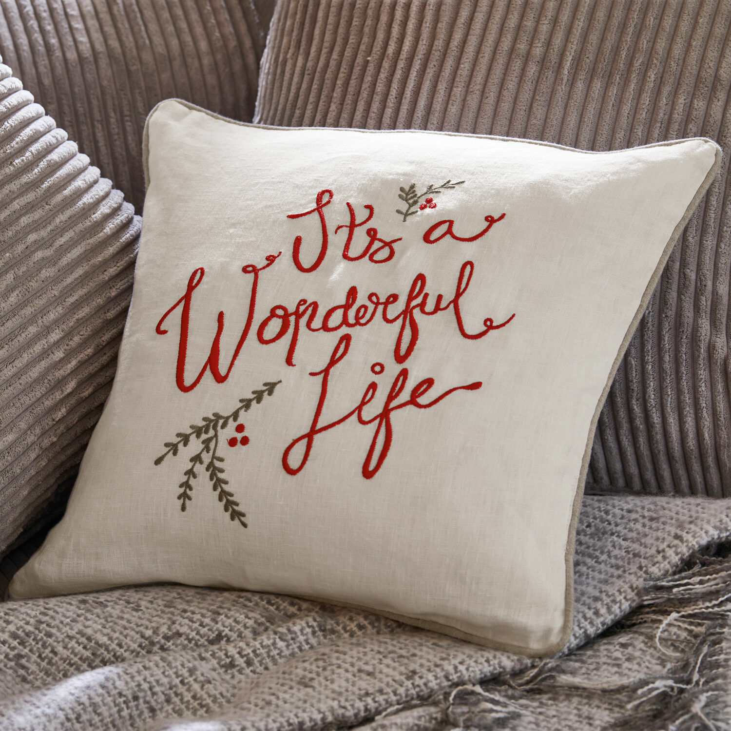 Kissenhülle Wonderful Beige Leinenkissen mit roter Stickerei "It's a Wonderful Life" auf grauem Stoff.