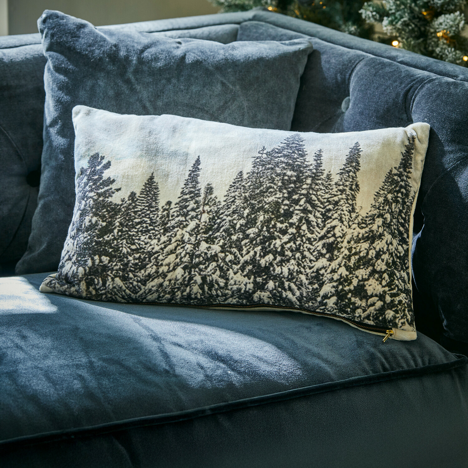 Kissenhülle Silver Creek Rechteckiges Dekokissen mit Winterwald-Motiv auf hellem Stoff auf dunkelblauem Samtsofa