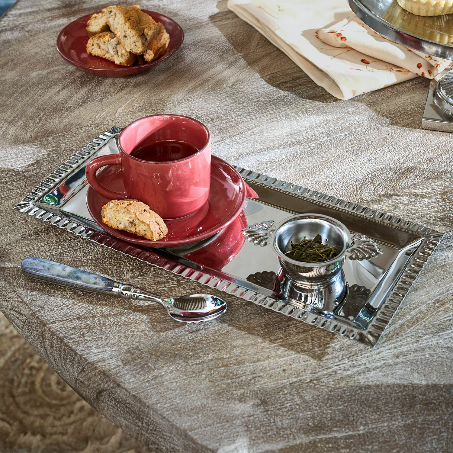 Teeset Arivelle Rechteckiges silbernes Metalltablett mit roter Tasse, Tee und Keks auf Holztisch