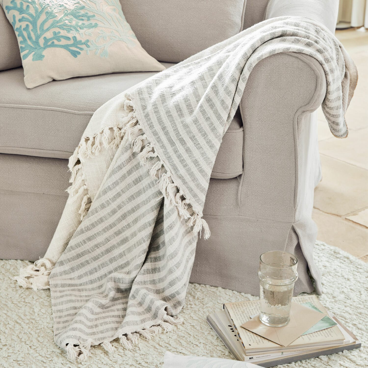 Plaid Marpent Beiger gestreifter Kuscheldecke mit Fransen auf hellgrauem Sofa, gemütliches Wohnaccessoire