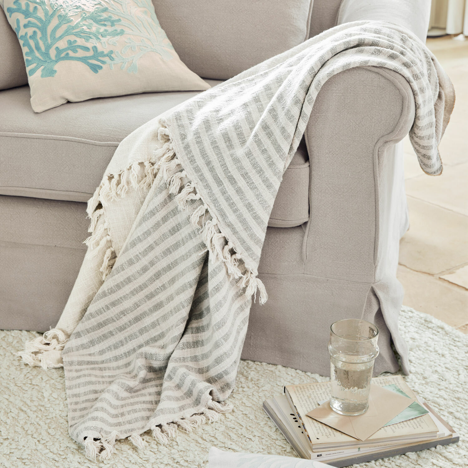 Plaid Marpent Beiger gestreifter Kuscheldecke mit Fransen auf hellgrauem Sofa, gemütliches Wohnaccessoire