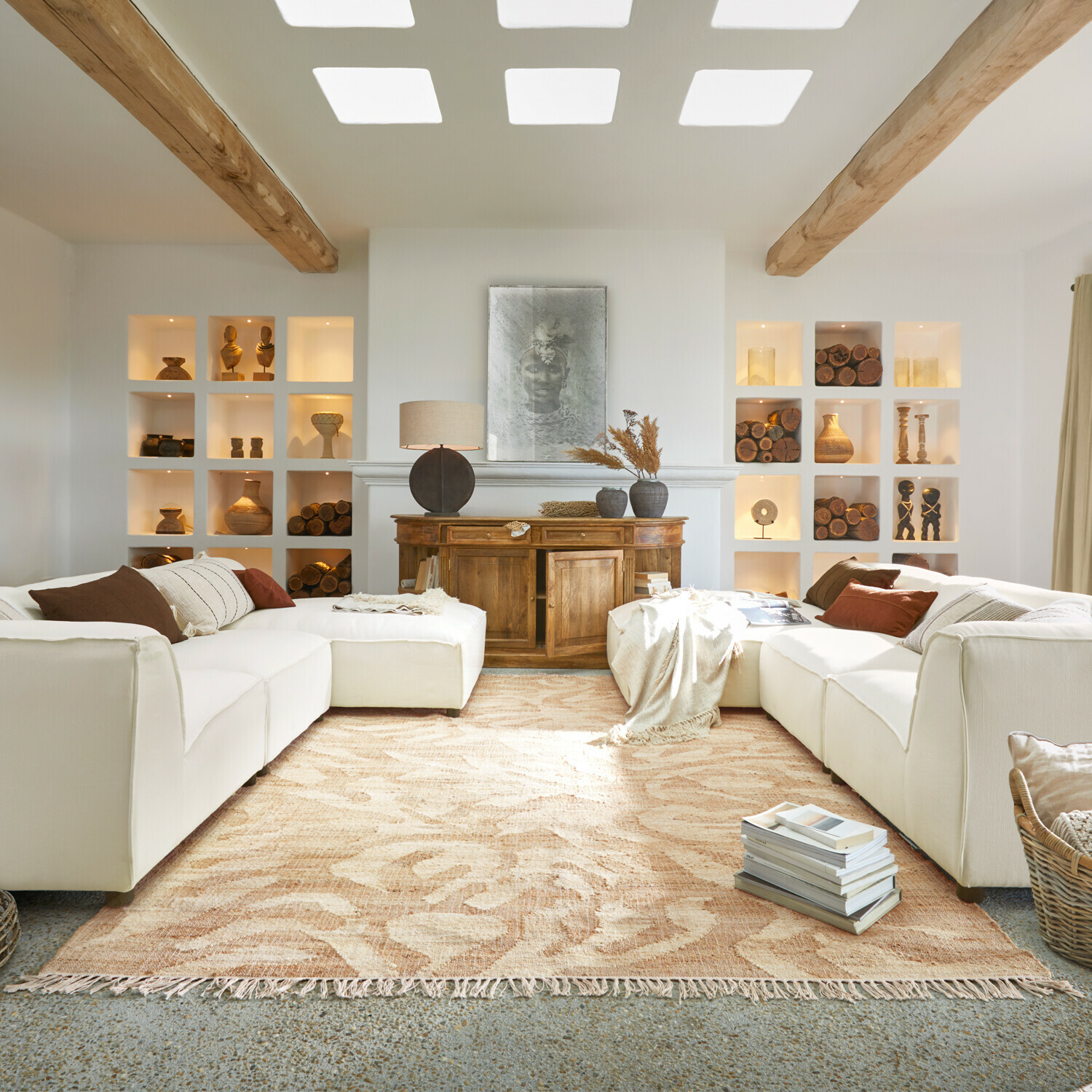 Gemütliches Wohnzimmer mit weißem Sofa, Holzkommode und beigem Teppich mit Pflanzenmuster, Holzdekorationen