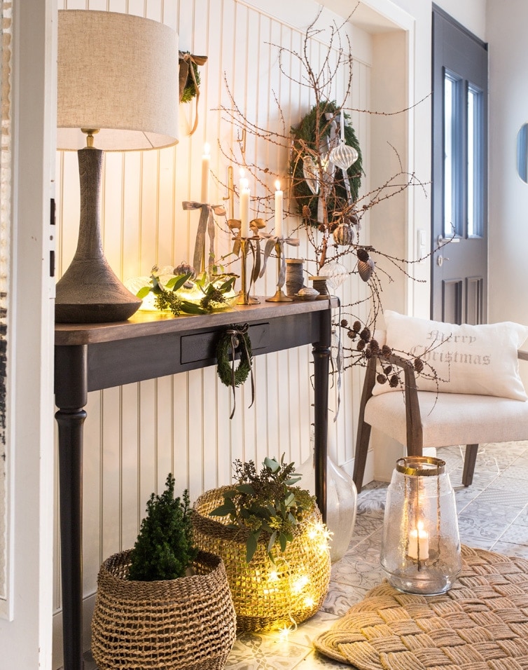 Gemütliches Interieur mit schwarzem Holztisch, Lampe und Weihnachtsdeko aus Korb und Kerzen