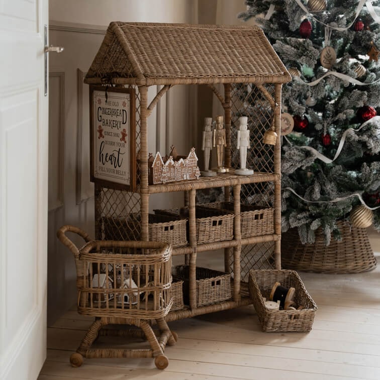 Natürlicher Rattanmöbel mit Körben und Weihnachtsdekorationen neben geschmücktem Baum