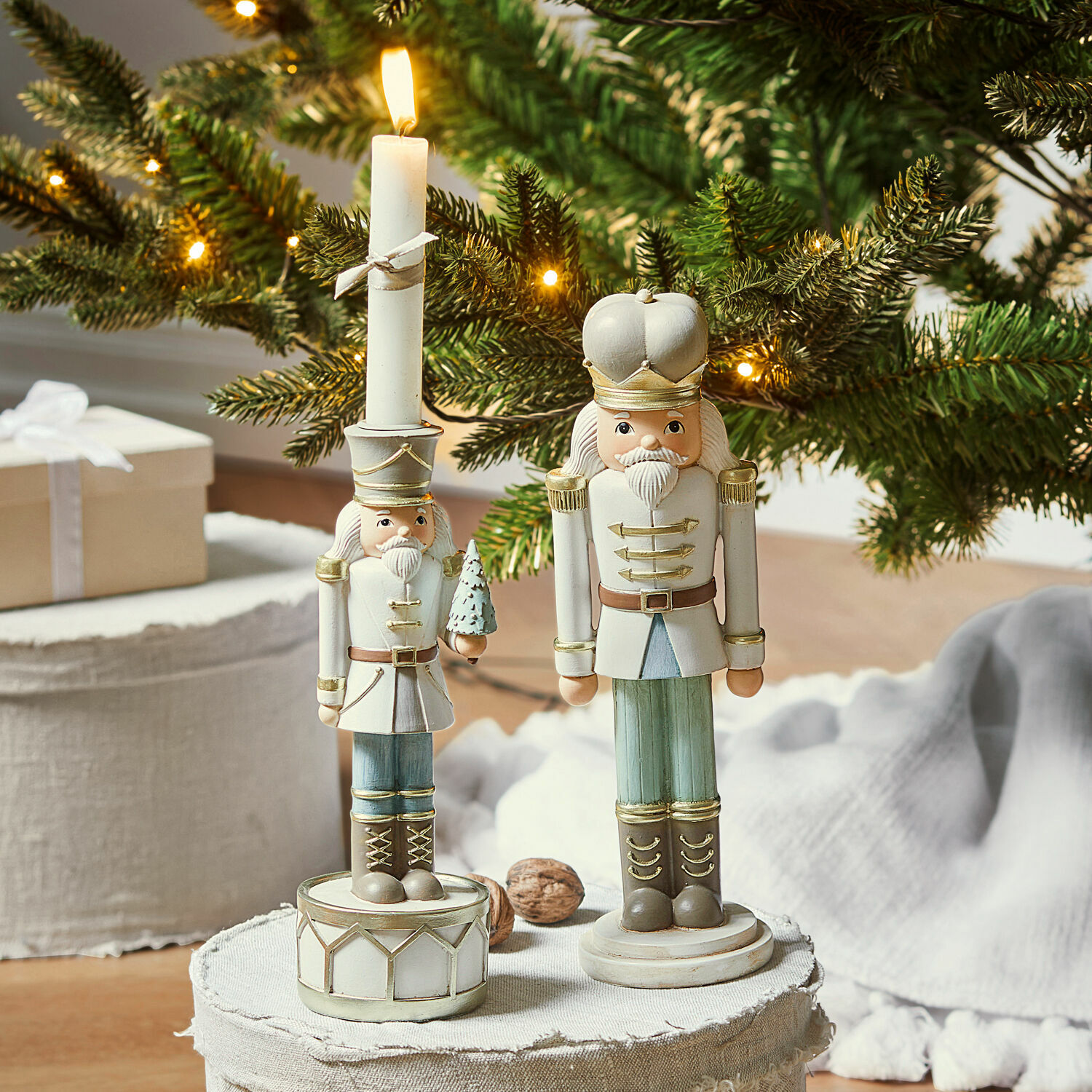 Deko-Nussknacker mit Kerzenständer Ellicott Zwei weiße und grüne Holz-Nussknackerfiguren vor weihnachtlich beleuchtetem Tannenzweig