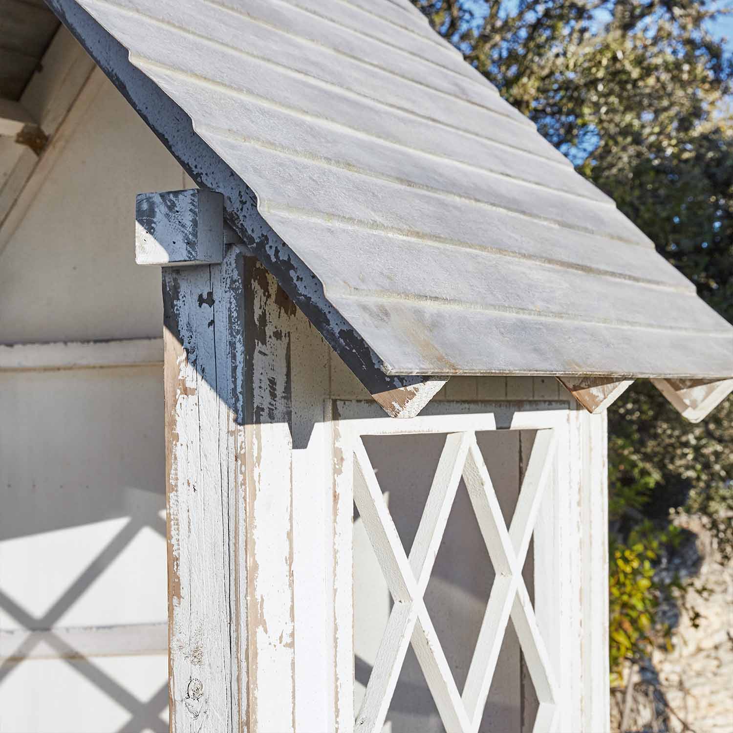 Weißes Holz-Gartenhaus mit abgenutztem Look und schrägem Dach im Außenbereich