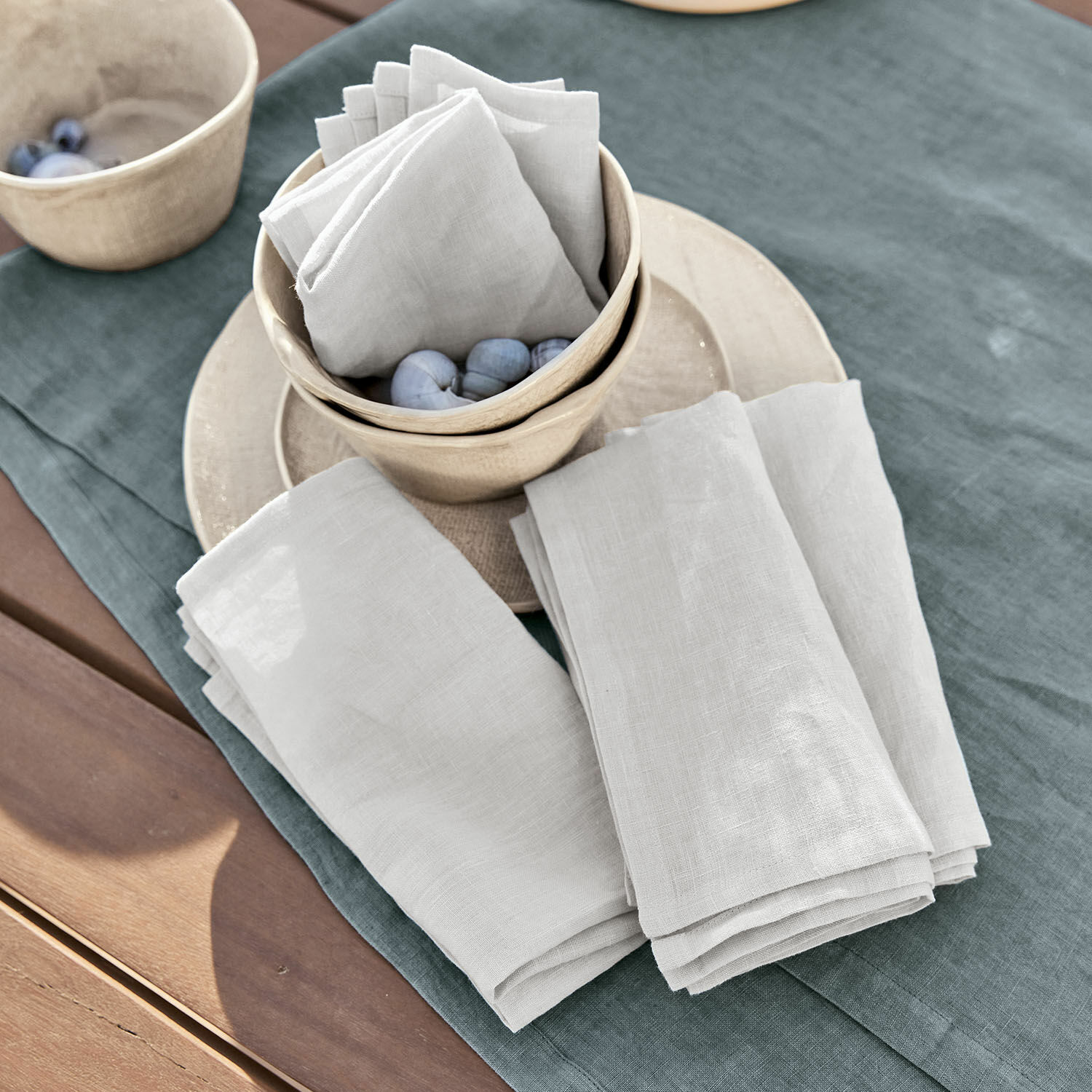 Serviette 4er Set Ghis Weiße Leinenservietten auf grünem Tischtuch mit Keramikschalen und Dekokugeln