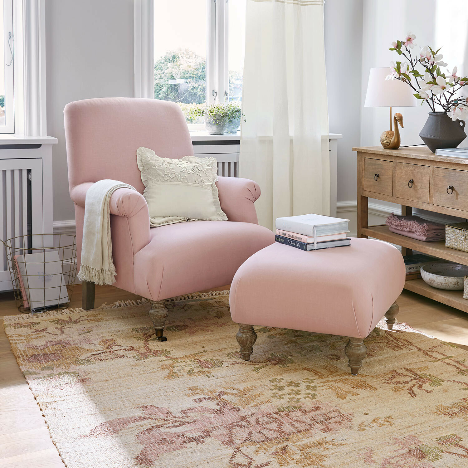 Sessel mit Hocker Rose de Lumière Rosa Sessel und Hocker aus Stoff in hellem Wohnzimmer mit Holztisch und Dekorationen
