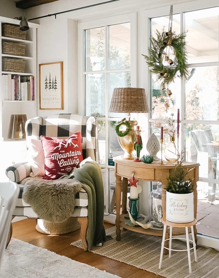 Gemütliche Ecke mit kariertem Sessel, Weihnachtsdeko und Lampe auf Holztisch im Wohnzimmer.