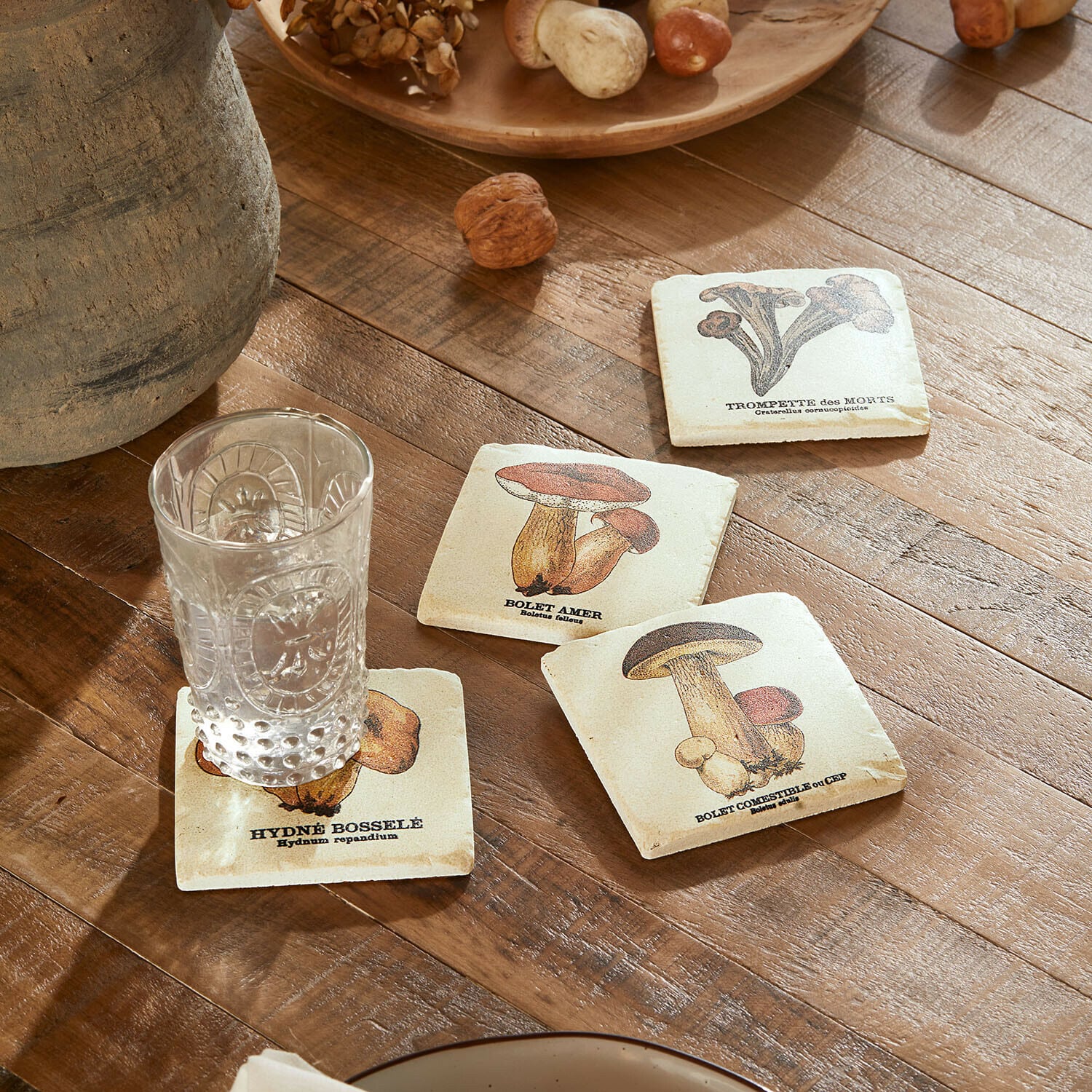 Untersetzer 4er Set Jandoria Untersetzer mit Pilzmotiven auf Holztisch mit klarem Glas und Walnüssen