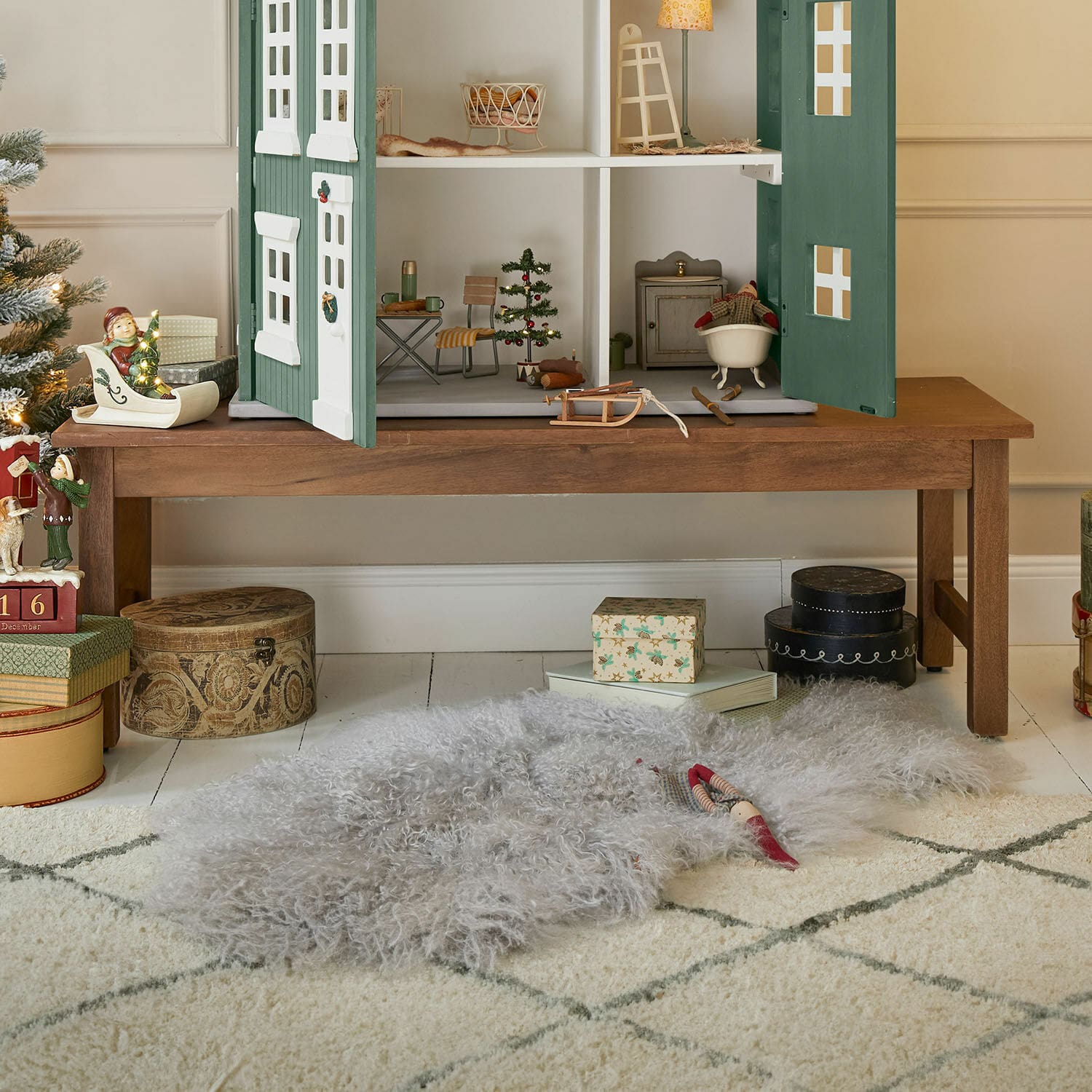 Bank Noireval Grauer weicher Wollteppich auf dem Boden unter einem Holztisch mit Puppenhaus und Weihnachtsdekoration