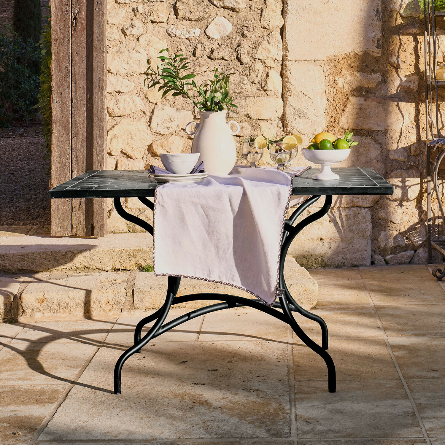 Tisch Maurelle Gartentisch mit schwarzem Metallgestell und Marmorplatte, dekoriert mit weißer Vase und Früchten
