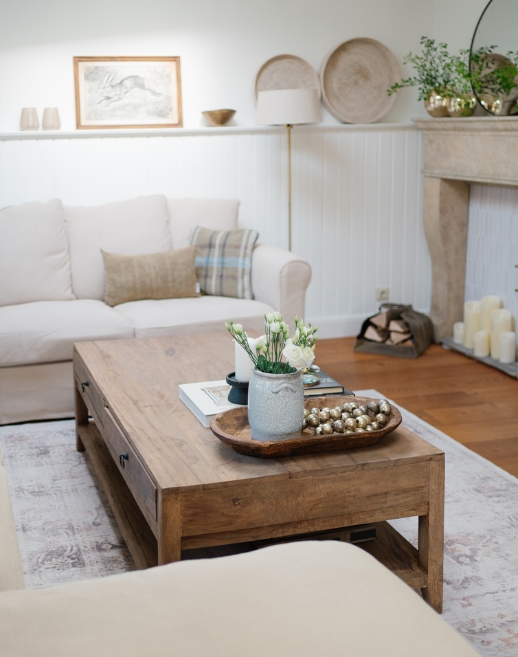 Wohnzimmer mit Holztisch und beigem Sofa, skandinavisch inspirierte Dekorationen