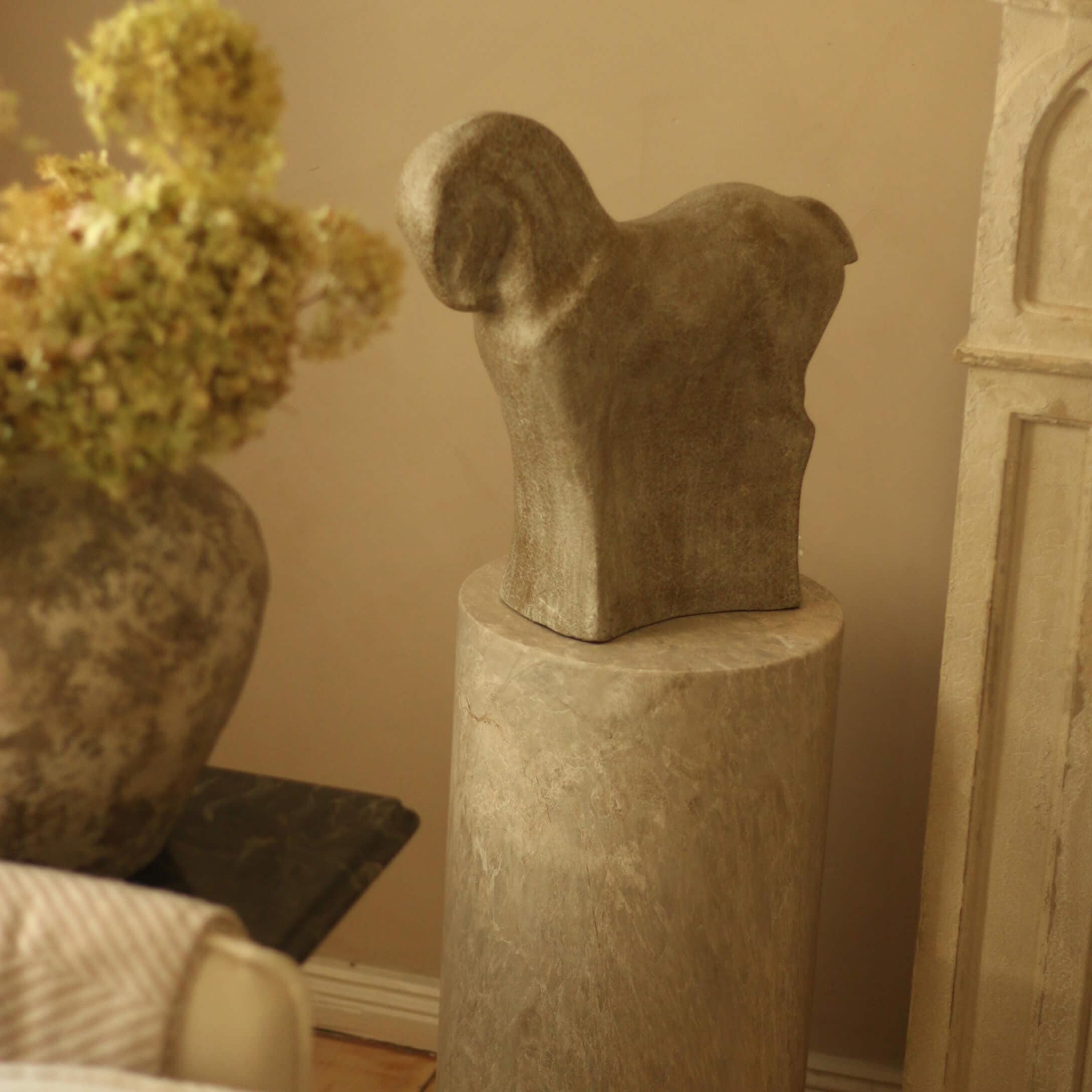 Steinskulptur in Tierform auf Marmorpodest in warmem Raumambiente