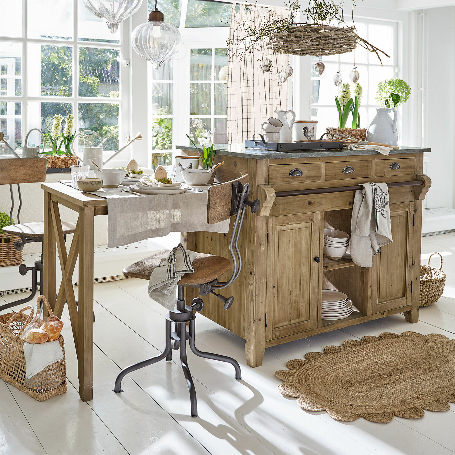 Rustikale Küche mit Holzinsel und Tisch, natürliche Materialien und helle Dekorationen in sonnigem Raum