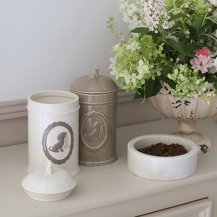 Keramikdosen in Creme und Beige für Hundefutter neben weißer Futterschale und Blumenarrangement