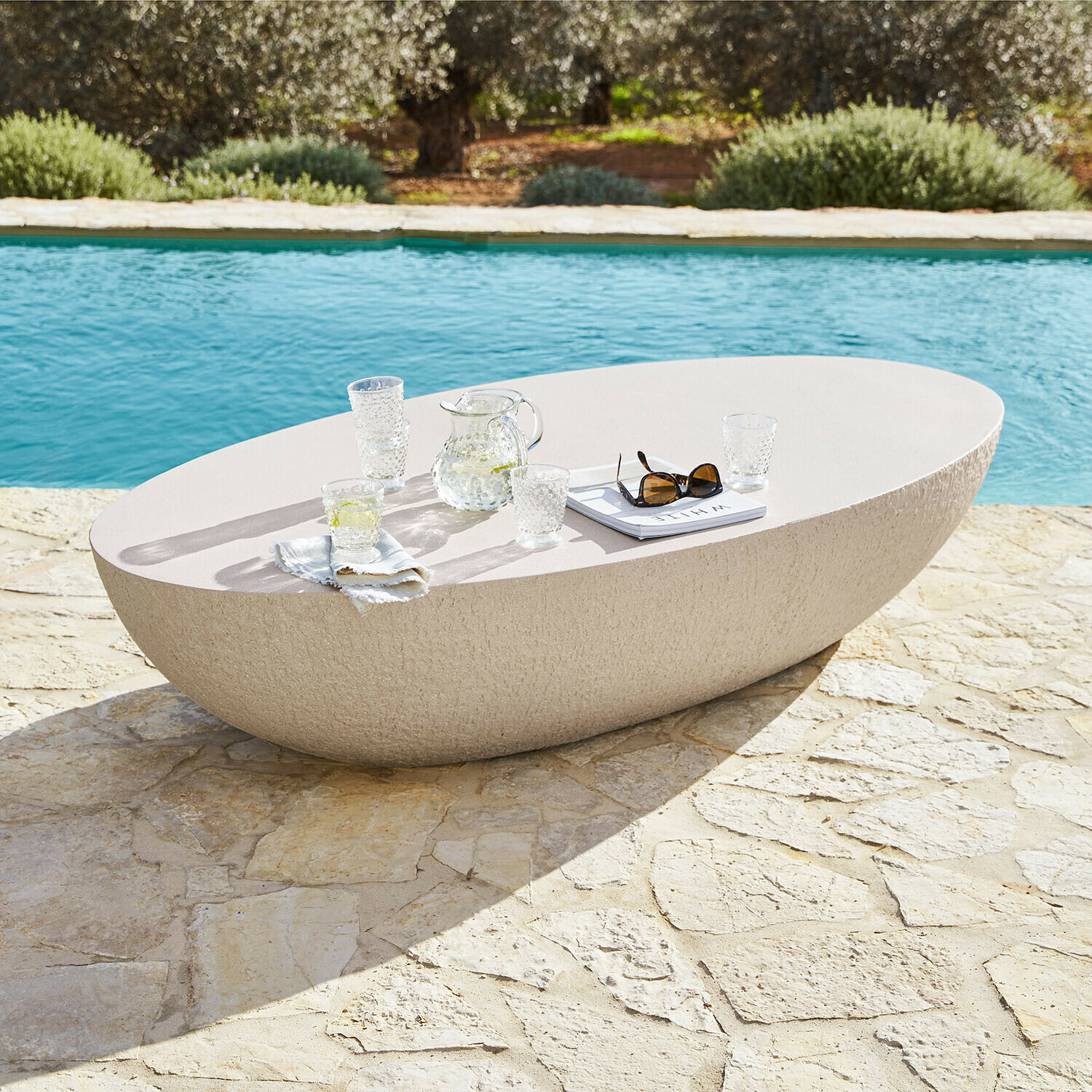 Couchtisch Maraveda Ovaler Gartentisch aus hellem Stein auf Naturstein-Terrasse am Pool, moderner Outdoor-Möbel