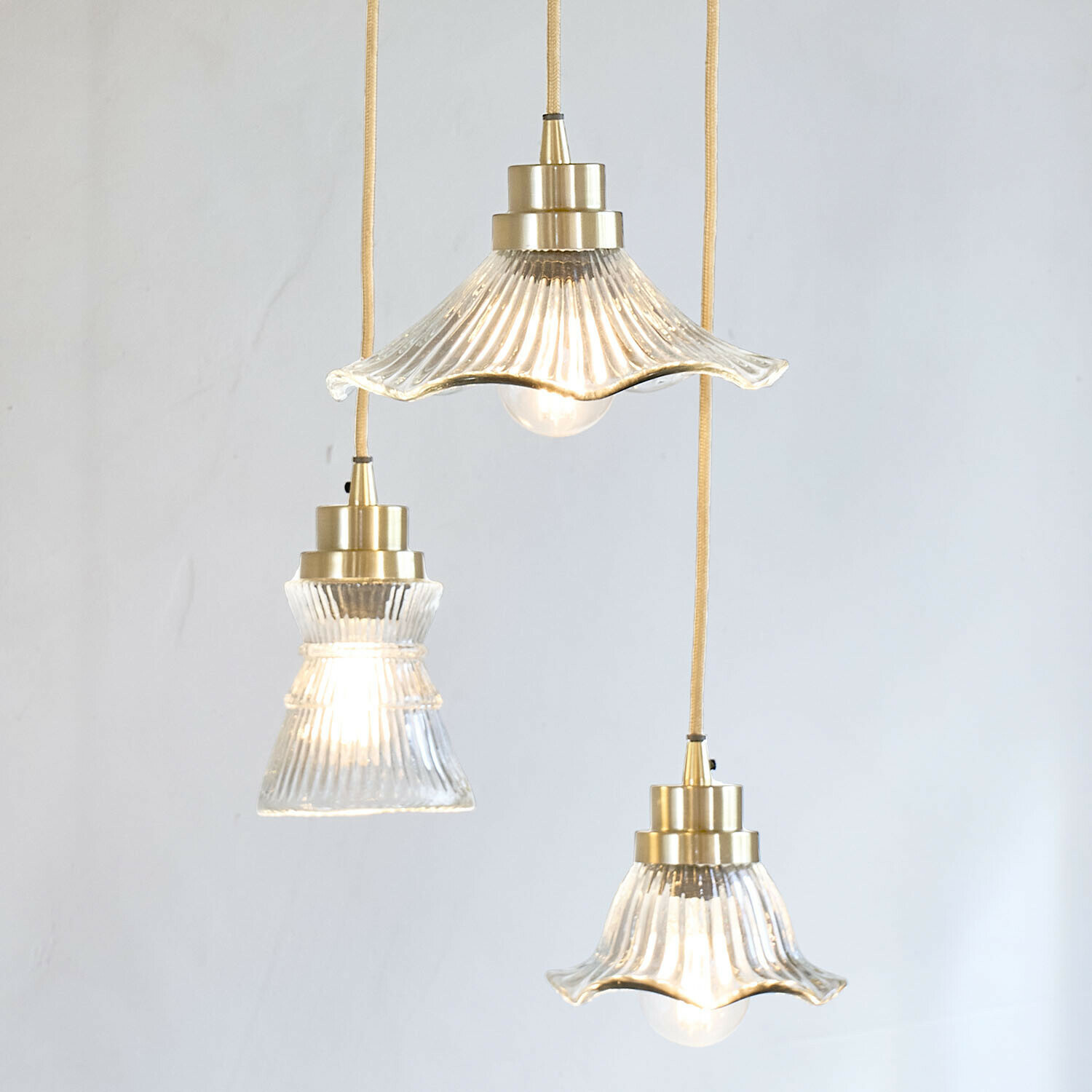 Drei hängende Glaslampen mit Messingdetails und gelbem Kabel für stilvolle Innenbeleuchtung