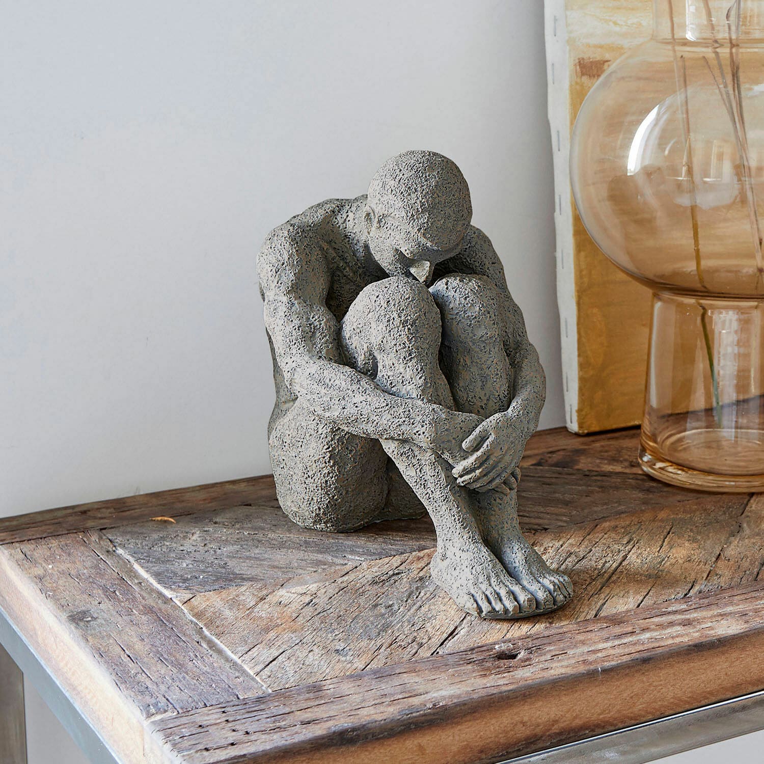 Figur Antony Graue Steinskulptur einer sitzenden Figur auf Holztisch, moderne Wohnraumdekoration