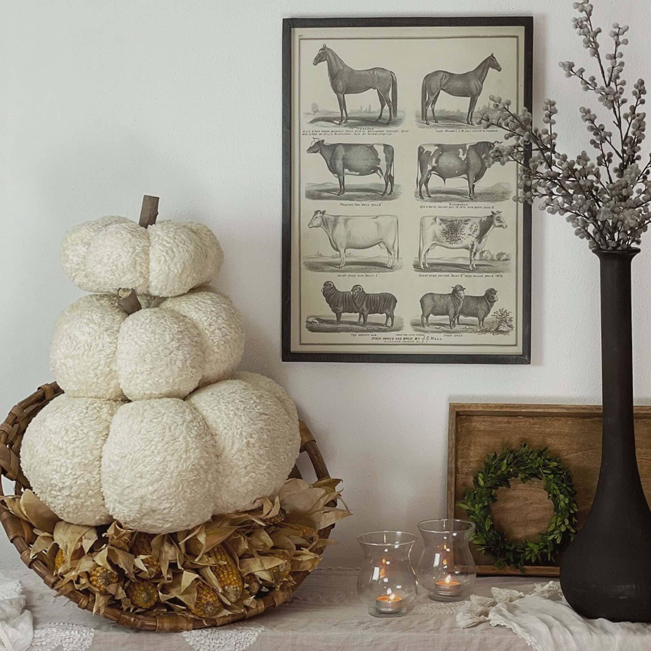 Herbstliche Dekoration mit weißem Plüschkürbis im Korb und Kerzen auf dem Tisch