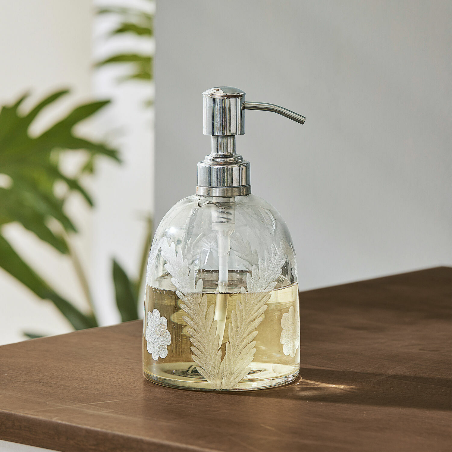 Seifenspender Crystal Glas-Seifenspender mit Metallpumpe und weißem Blattmuster auf braunem Holztisch
