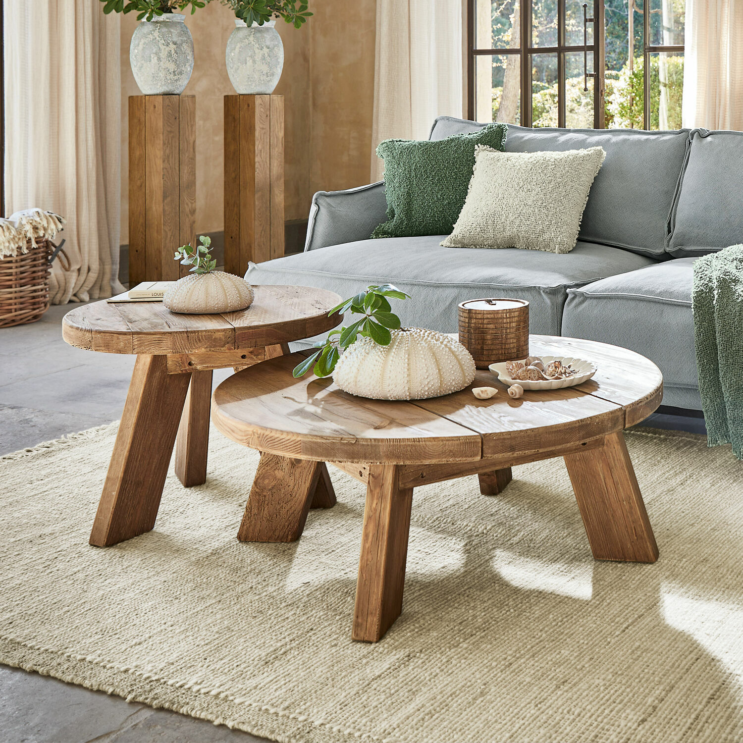 Couchtisch 2er Set Oteley Zwei runde Couchtische aus Holz in Naturfarbe auf hellem Teppich vor grauem Sofa im Wohnzimmer