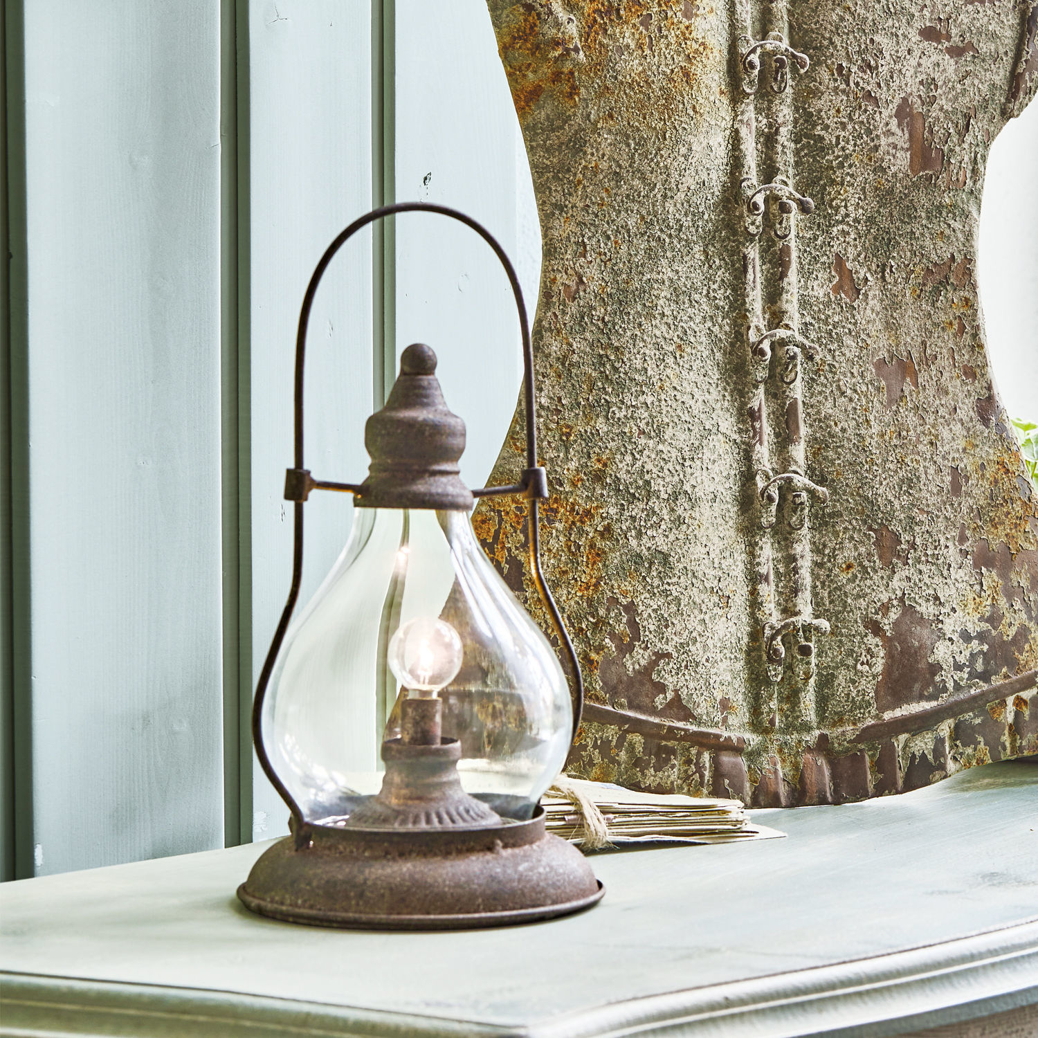 Rustikale Tischlampe aus rostigem Metall auf hellem Holztisch im Vintage-Stil