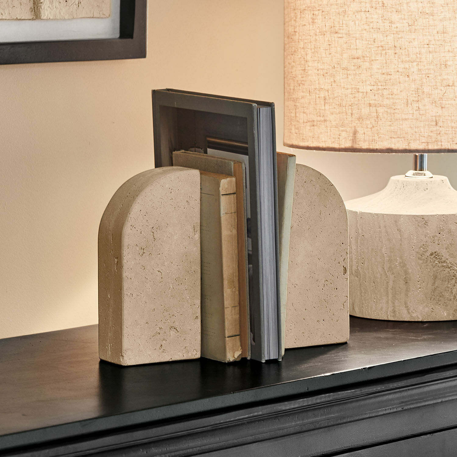 Beige Buchstützen aus Stein mit abgerundeter Form auf schwarzem Regal im Wohnzimmer