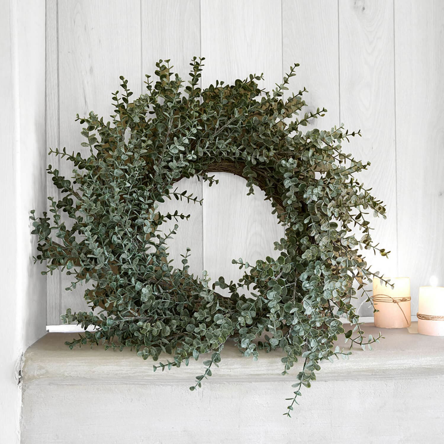 Dekorativer Kranz aus grünen Eukalyptusblättern auf hellem Hintergrund, natürliche Wohnraumdeko