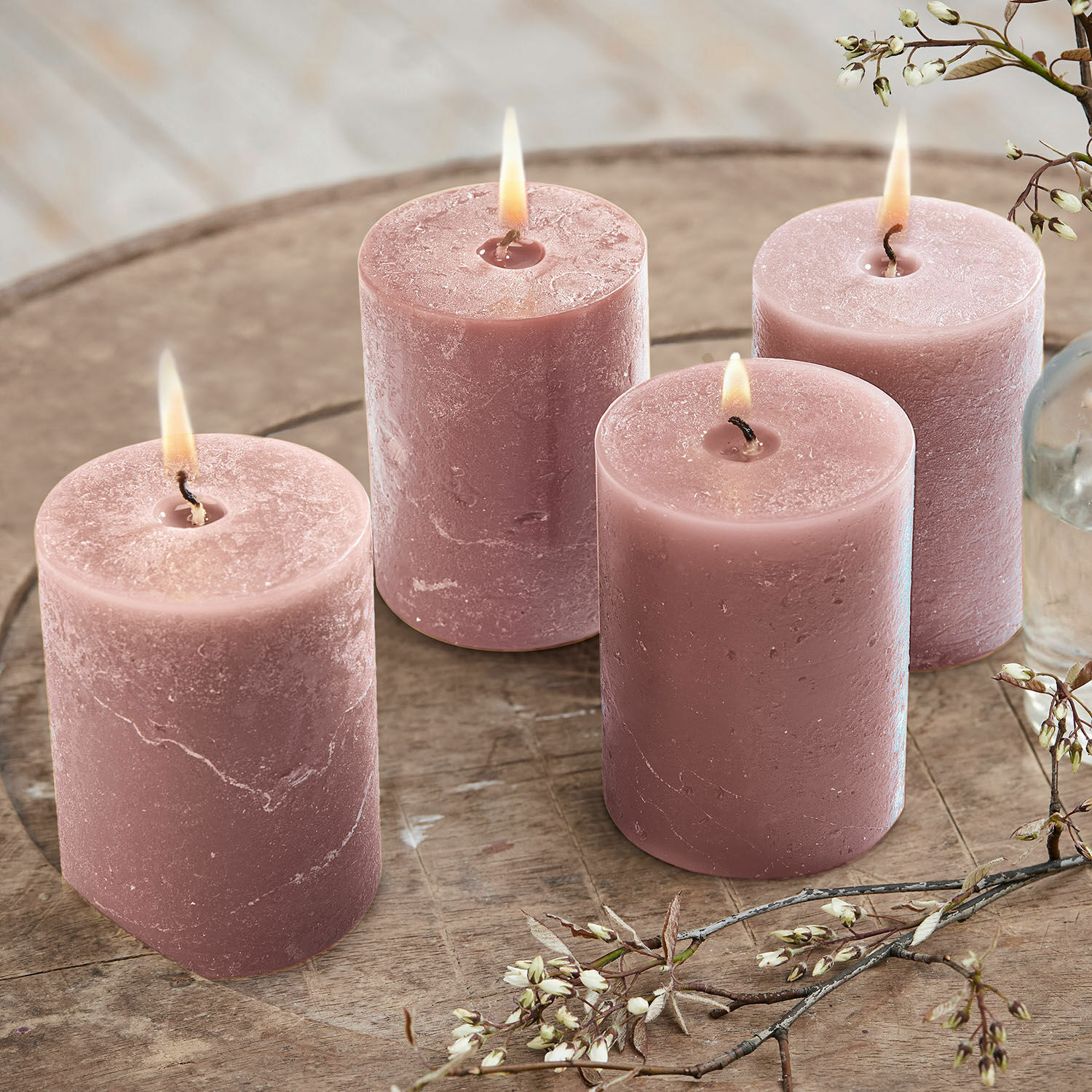 Kerze 4er Set Virrans Set aus vier rosa Kerzen aus Wachs auf Holztisch mit Blumenarrangement