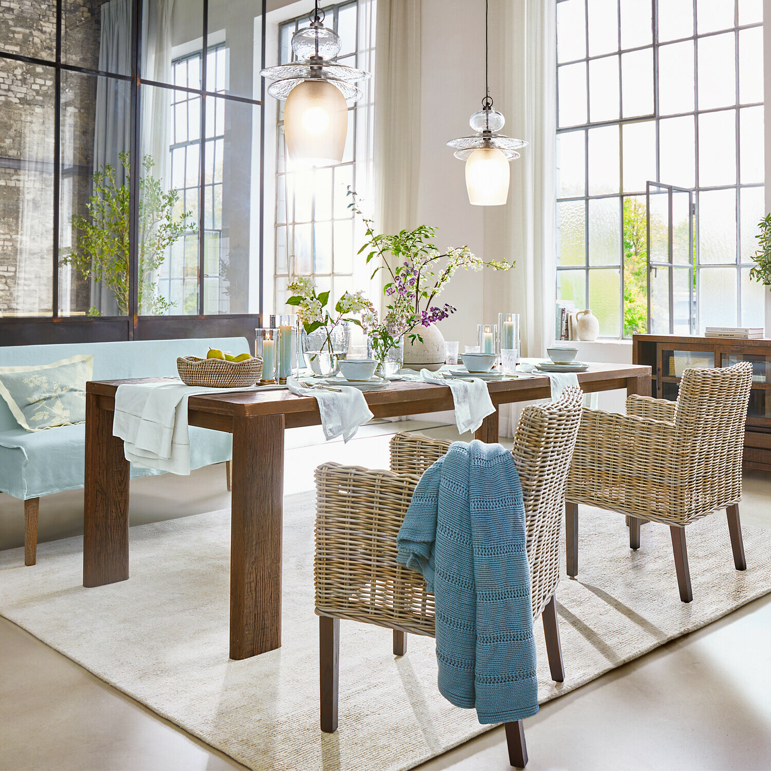 Esszimmer mit Holztisch, Rattanstühlen und dekorativer rustikaler Beleuchtung