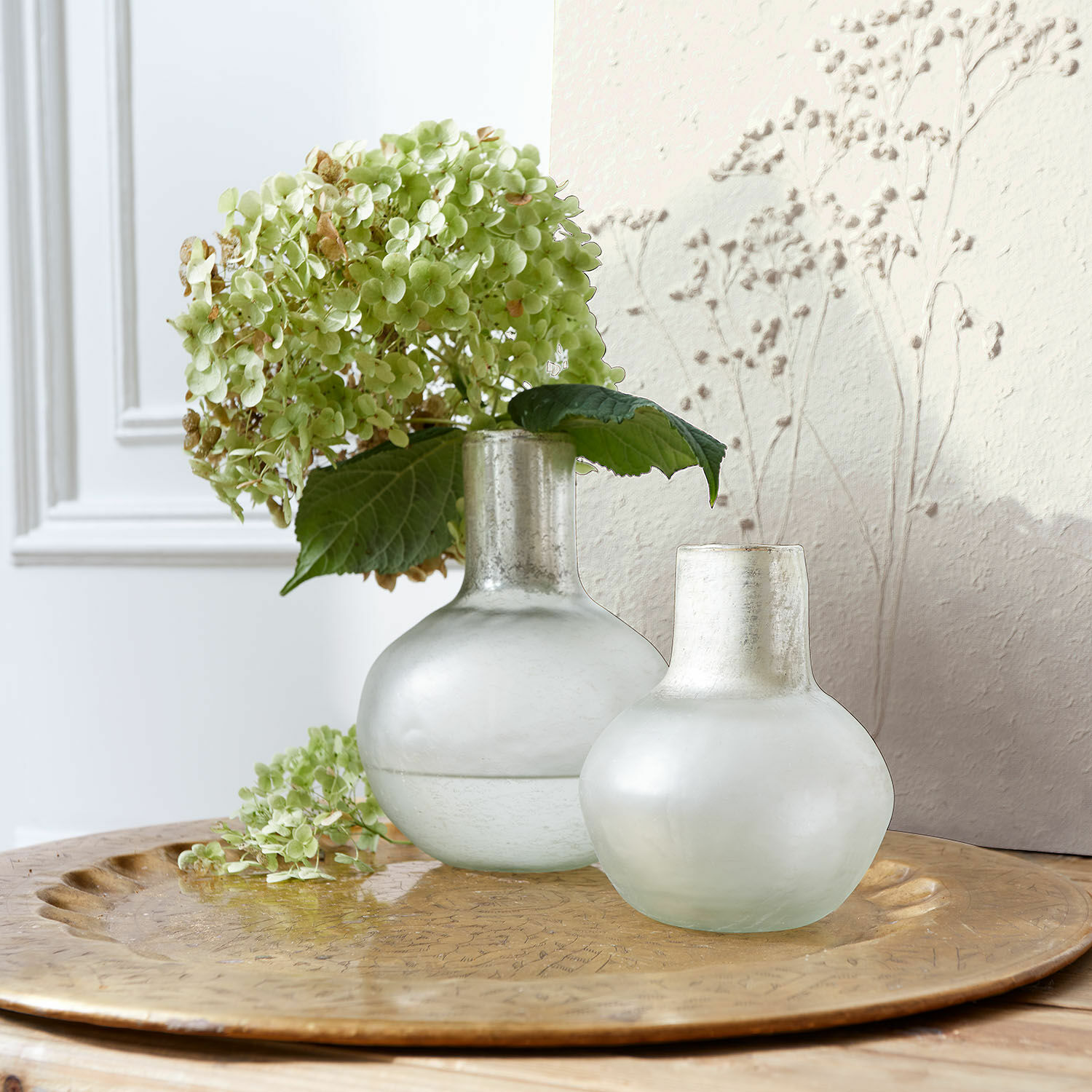 Vase 2er Set Nazira Zwei matte milchglasfarbene Vasen auf goldfarbenem Tablett mit grünen Hortensienblüten