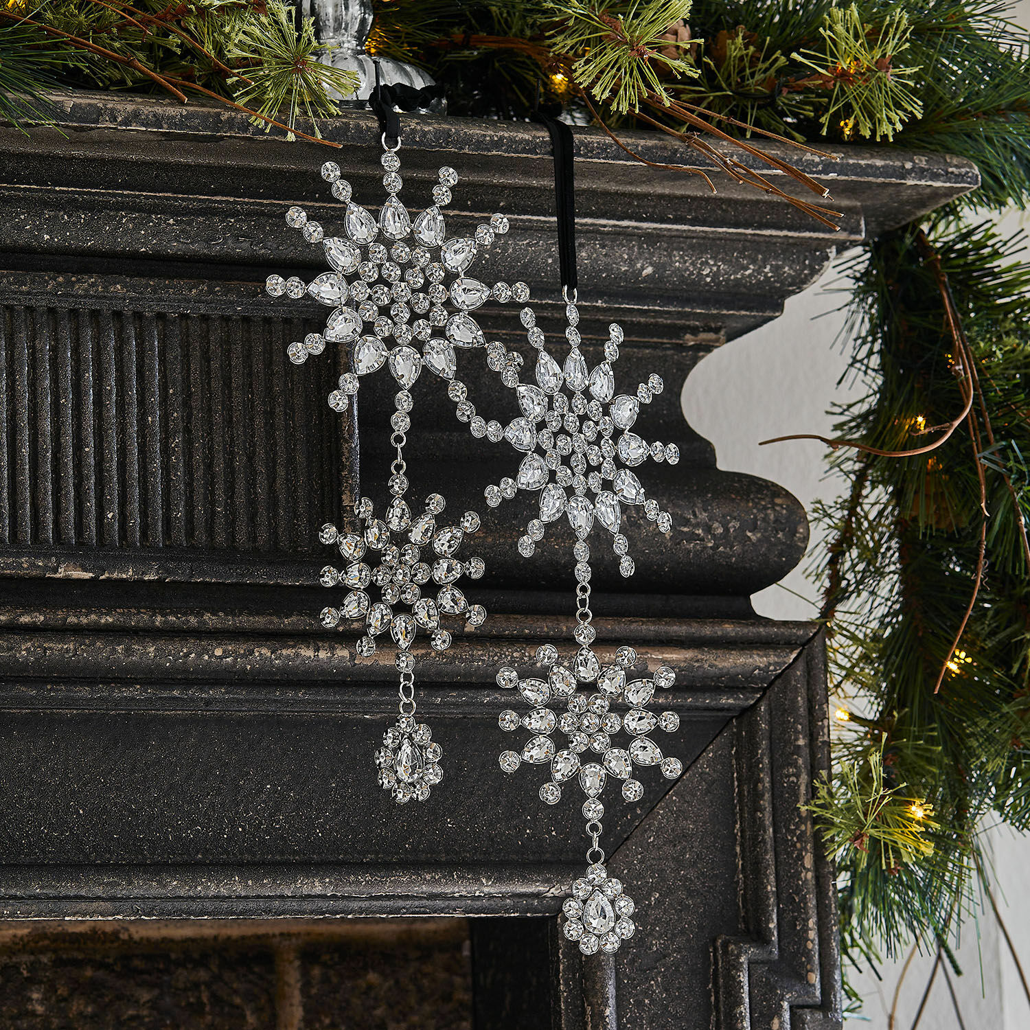 Weihnachtsanhänger 2er Set Klerven Weihnachtliche Dekoration aus transparenten Kristallen in Schneeflockenform an schwarzem Kamin mit grünen Zweigen