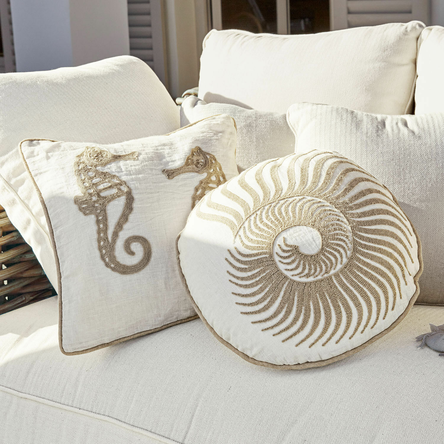 Kissen 2er Set Bristol Dekorative Baumwollkissen in Creme mit Seepferdchen- und Muschelmotiv auf hellem Sofa