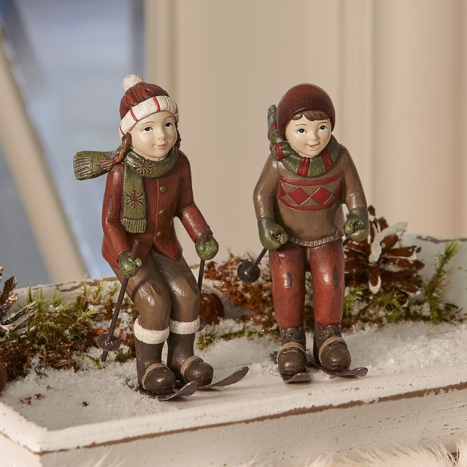 Figur 2er Set Bibury Figuren von Kindern in braun-roter Kleidung beim Skifahren als winterliche Weihnachtsdekoration