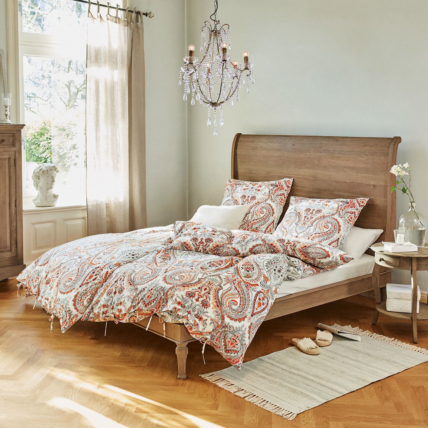 Bett Saint-Germier Schlafzimmer mit Holzbett und Bettwäsche im roten Paisley-Muster, Teppich und Kristallleuchter