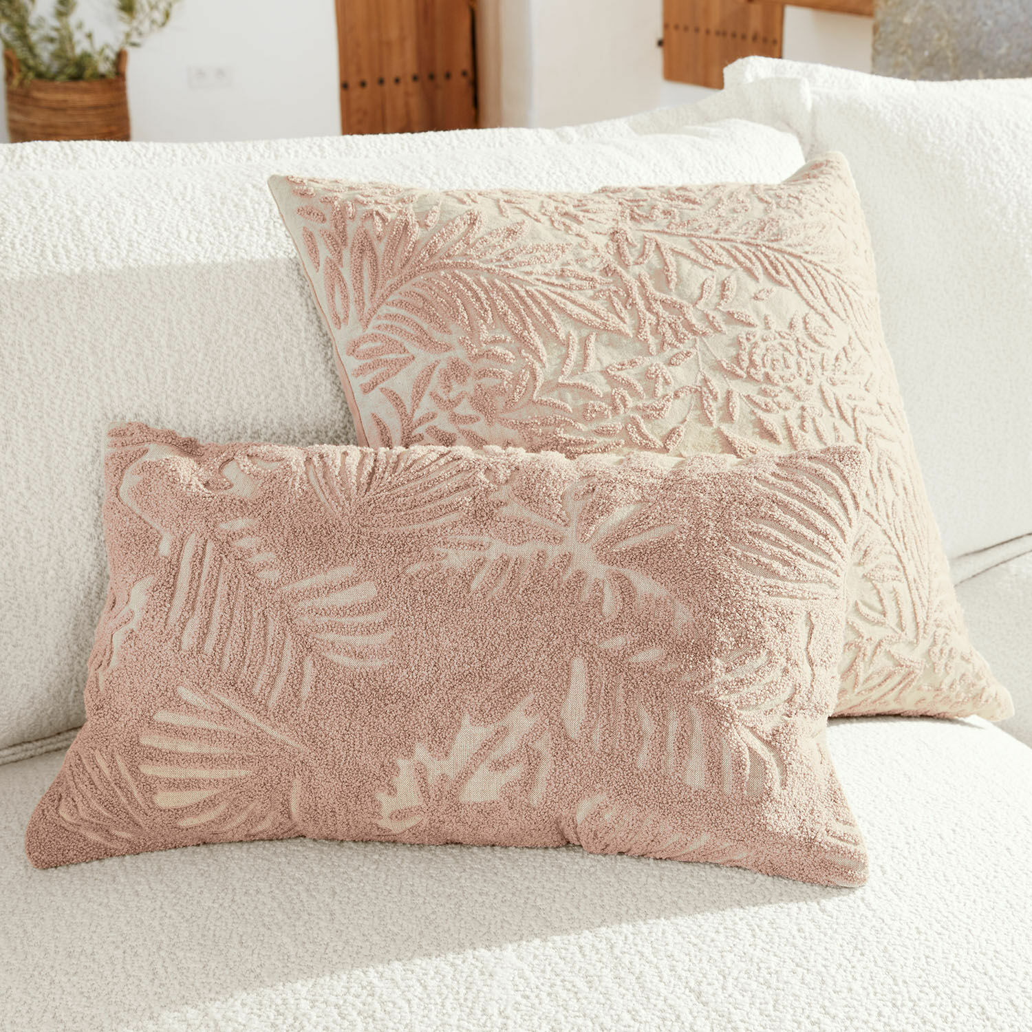Kissenhülle 2er Set Enchanto Zwei dekorative Kissen mit rosafarbenem Blattmuster auf cremefarbenem Grund auf weißem Sofa