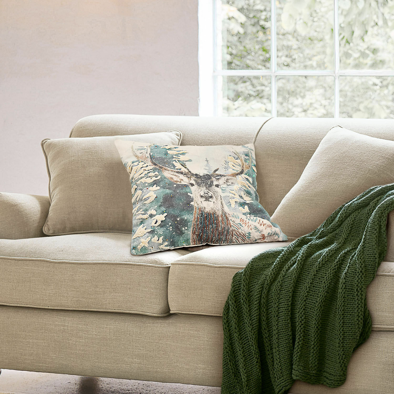Kissenhülle Elvaris Beiges Sofa mit dekorativem Kissen mit Hirschmotiv und grünem Strickplaid im Wohnzimmer