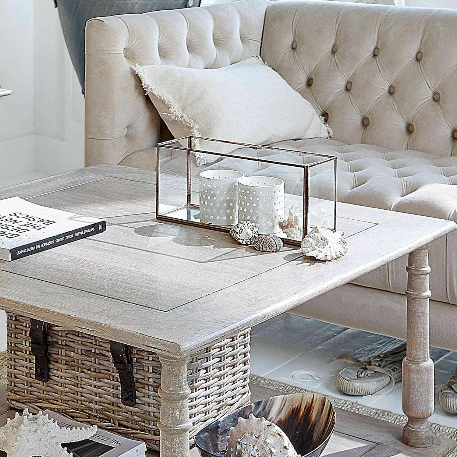 Windlicht Flavin Heller Holzcouchtisch mit Korb und Dekoration vor beigem, gesteppter Sofa im Wohnzimmer